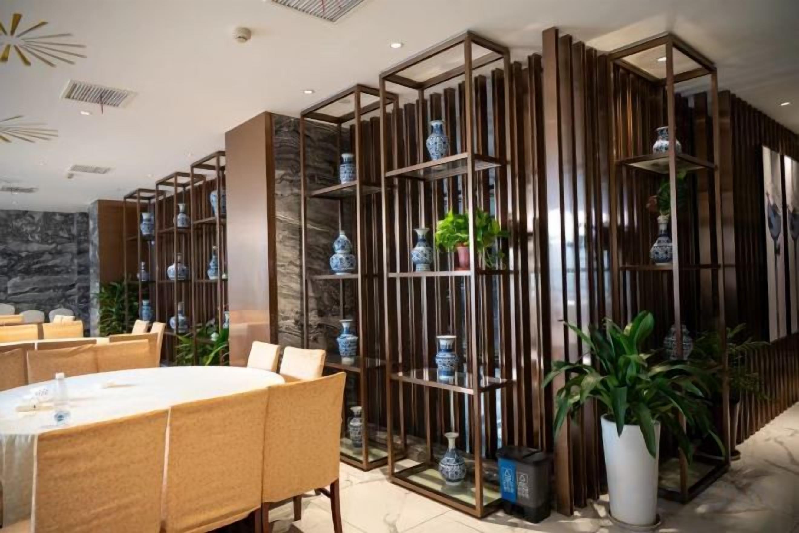Un comedor con una mesa redonda, sillas y una pared decorativa con estantes.