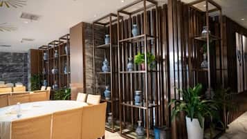 Un comedor con una mesa redonda, sillas y una pared decorativa con estantes.