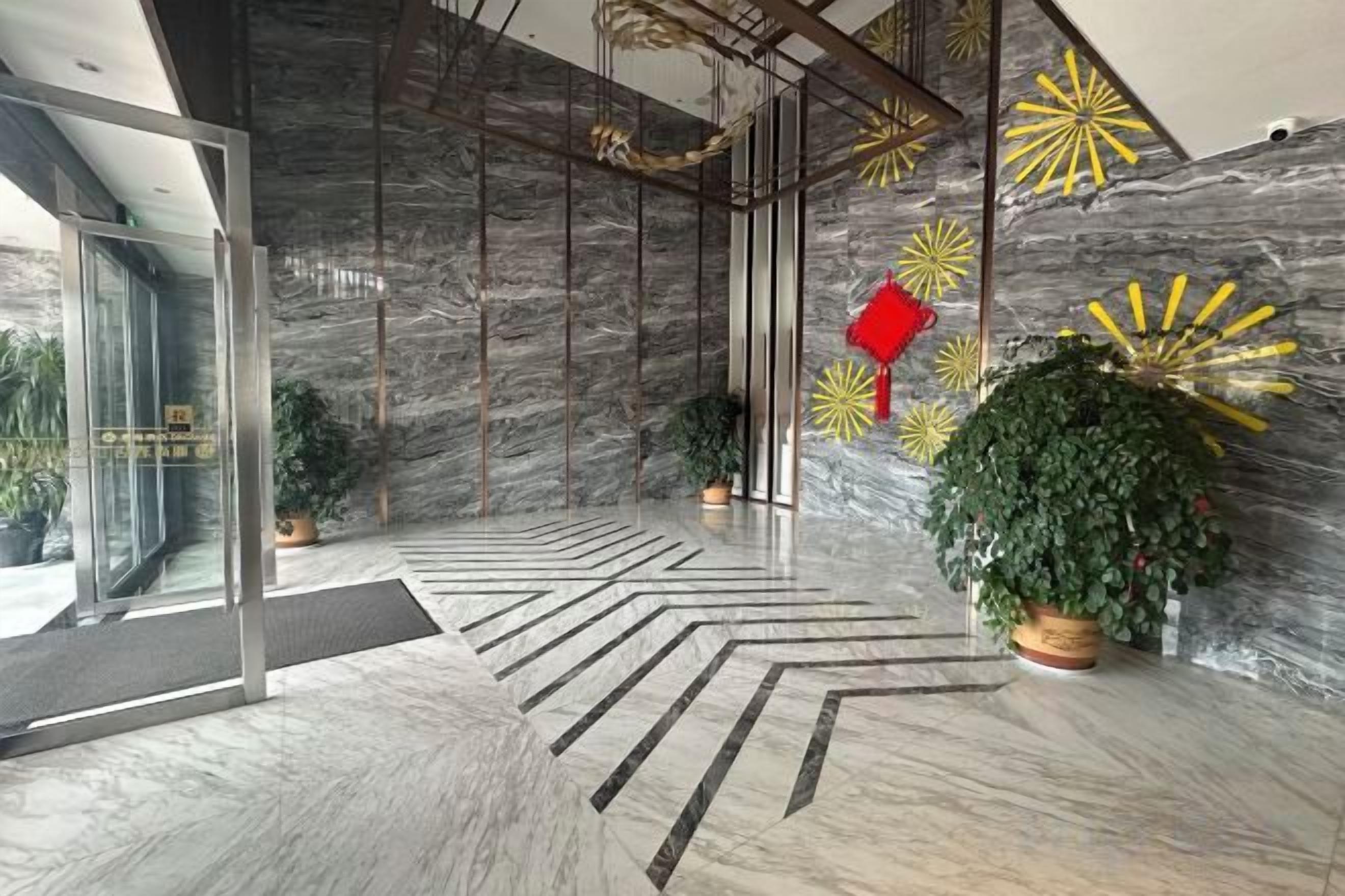 A modern lobby with a marble floor, glass doors, and decorative wall art.