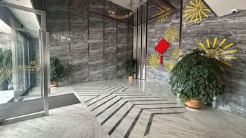 A modern lobby with a marble floor, glass doors, and decorative wall art.