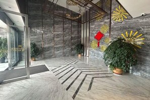 A modern lobby with a marble floor, glass doors, and decorative wall art. - Dingshang Hotel (Wuxi)
