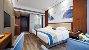 A hotel room with a bed, bedside table, chair, desk, and a large window. - Dingshang Hotel (Wuxi)
