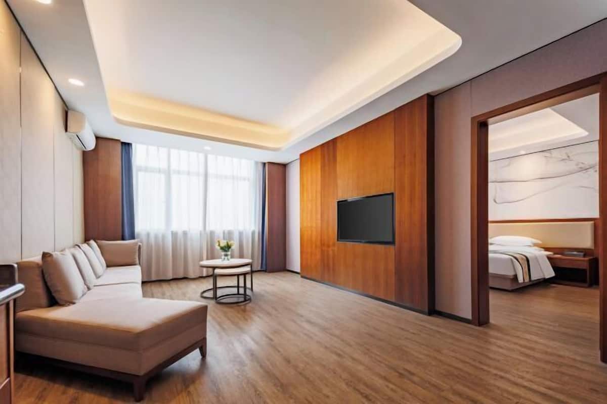 A modern hotel room with a sofa, a TV, a small table, and a bed.