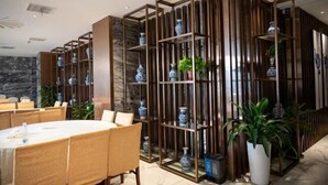 A modern dining area with a round table, chairs, and a decorative plant. - Dingshang Hotel (Wuxi)