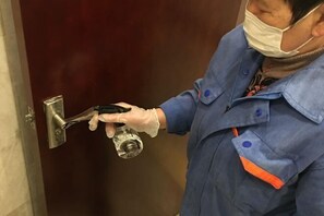 Una persona con uniforme azul y detalles naranja, sosteniendo una llave y un candado, manipulando el mecanismo de una cerradura.