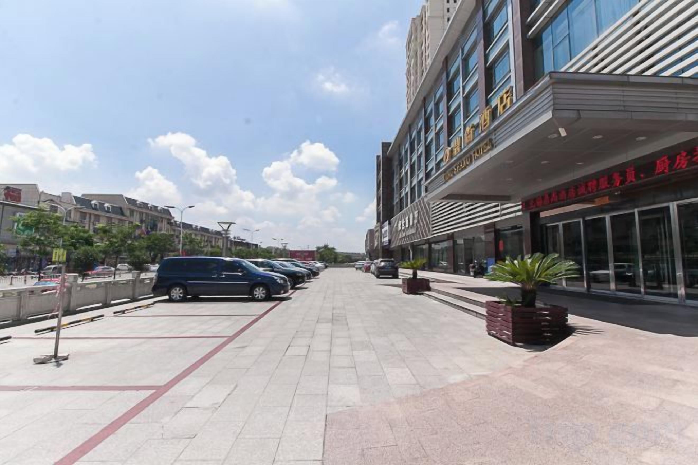 A paved walkway with parked cars, a building with signage, and a clear sky.