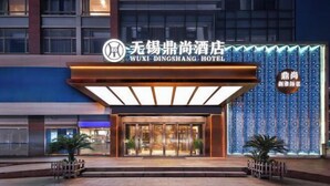 The exterior of Wuxi Dingshang Hotel with a modern facade, illuminated entrance, and decorative wall panels. - Dingshang Hotel (Wuxi)