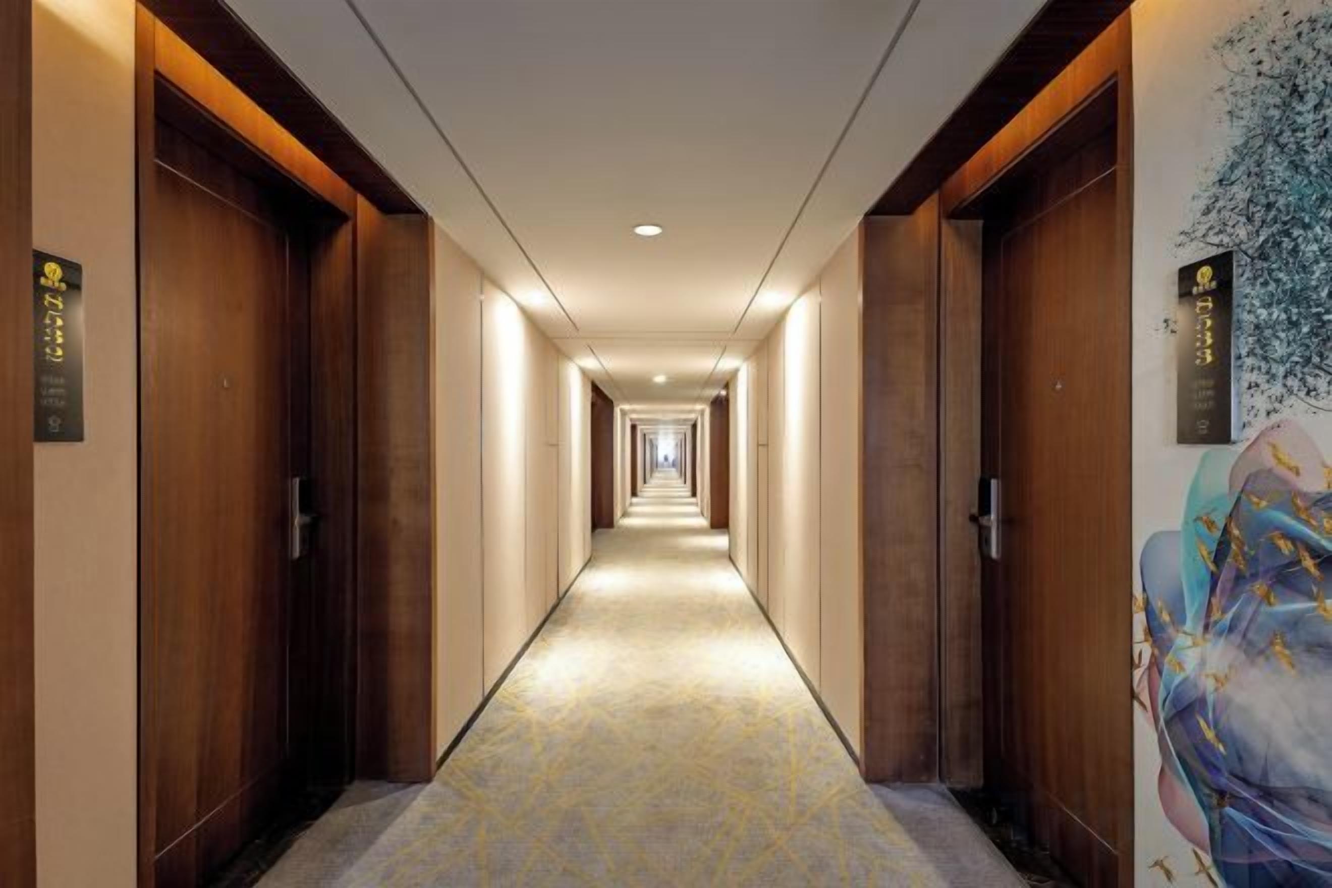 A hotel hallway with wooden doors, a patterned carpet, and a wall with a floral mural.