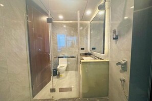 Un baño moderno con ducha envuelta en vidrio, inodoro y lavamanos.