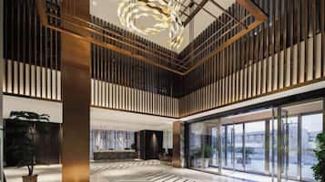 A spacious lobby with a high ceiling, modern lighting, and large windows.