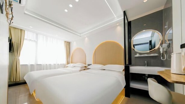 A hotel room with a large bed, a bedside table, a mirror, and a view of the outside.