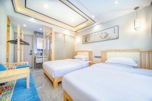 A hotel room with two beds, a desk, a chair, a wardrobe, and a bathroom.
