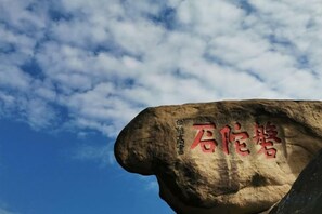 Un rocher orné de gravures, un ciel dégagé et quelques nuages.