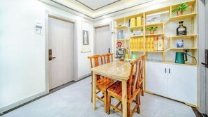 A dining area with a wooden table and chairs, a white cabinet with shelves, and a ceiling light fixture.