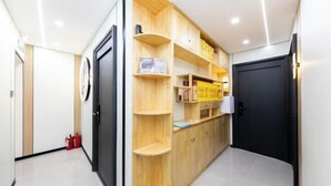 A hallway with a wooden storage unit, a black door, and a fire extinguisher.