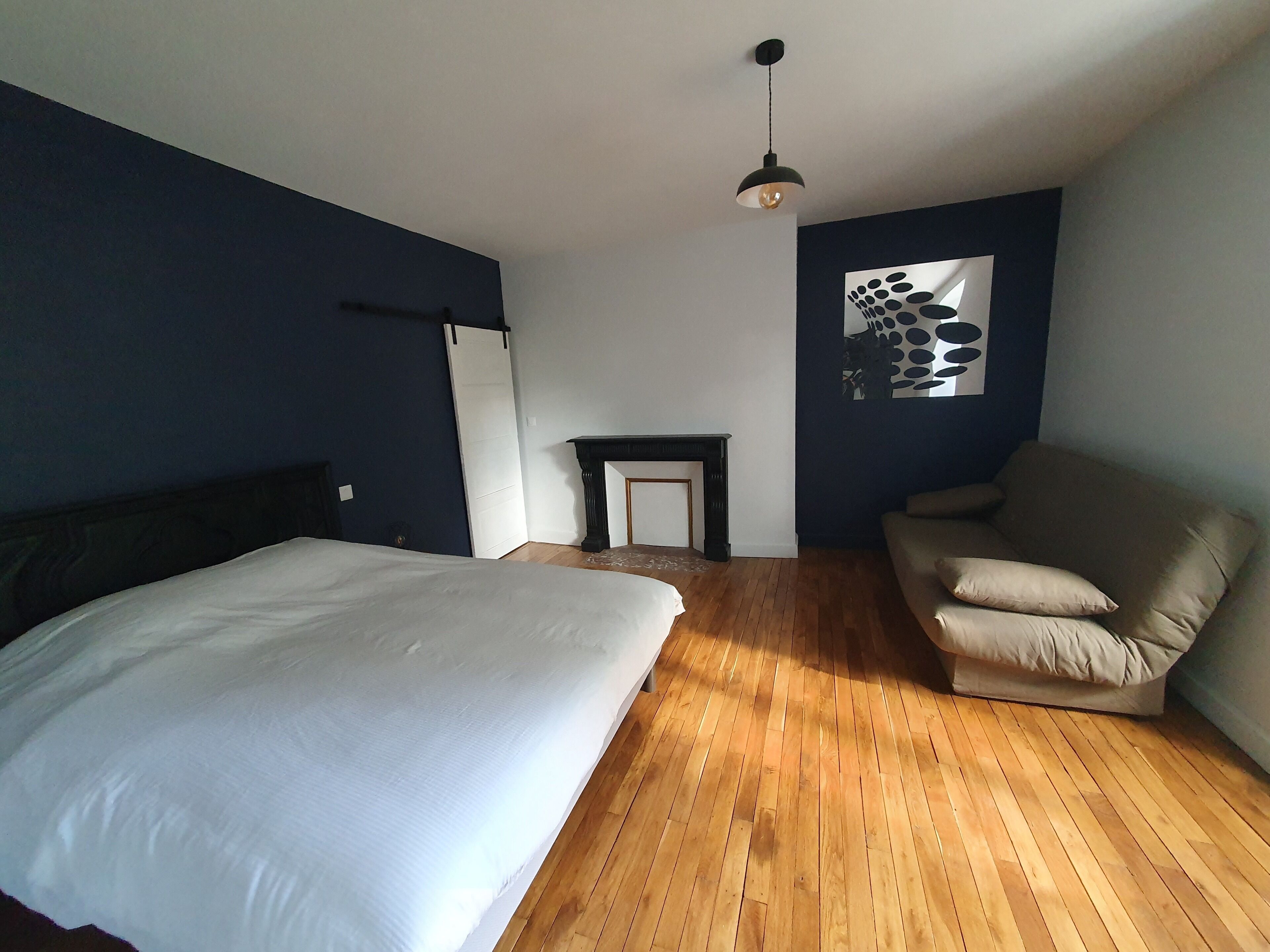 Un dormitorio con una cama grande, un sofá, una chimenea y una lámpara en el techo.