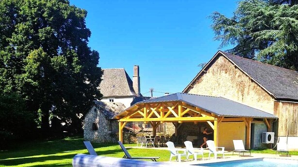A backyard with a swimming pool, a covered patio area, and a stone building. - Maison Rénovée Avec Terrasse + Parc Avec Piscine Chauffée et Terrasse Couverte (Estivaux)