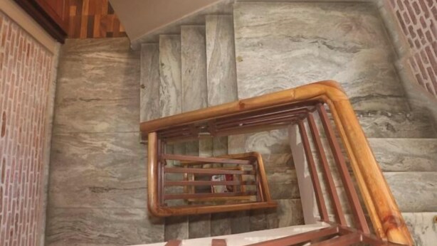 A staircase with a wooden handrail and a stone wall.