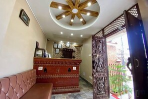 A reception area with a wooden reception desk, a bench, and a ceiling fan. - Hotel Vacation Home (Kathmandu)