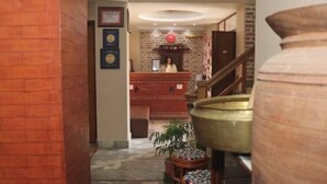A lobby area with a reception desk, a staircase, and a large decorative urn.