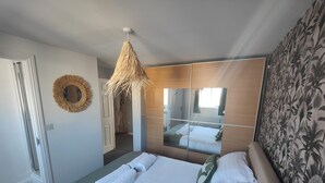Una camera d'albergo con un letto, uno specchio, una lampada a sospensione, una porta e una parete decorata.