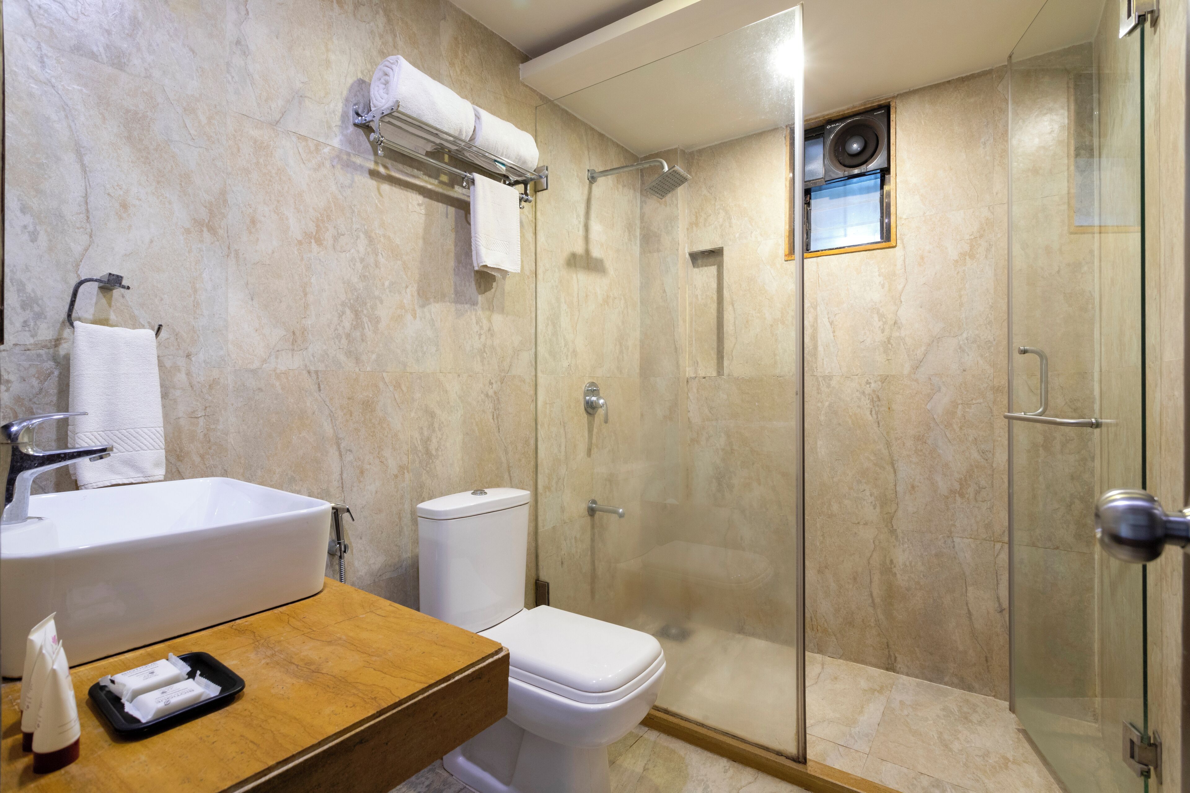 Un baño moderno con ducha envuelta en vidrio, lavamanos blanco y un inodoro.