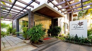A modern building with a glass entrance, a wooden pergola, and a sign for 'Riva Boutique Apartments'. - Riva Boutique Apartments (Alto de Porvorim)