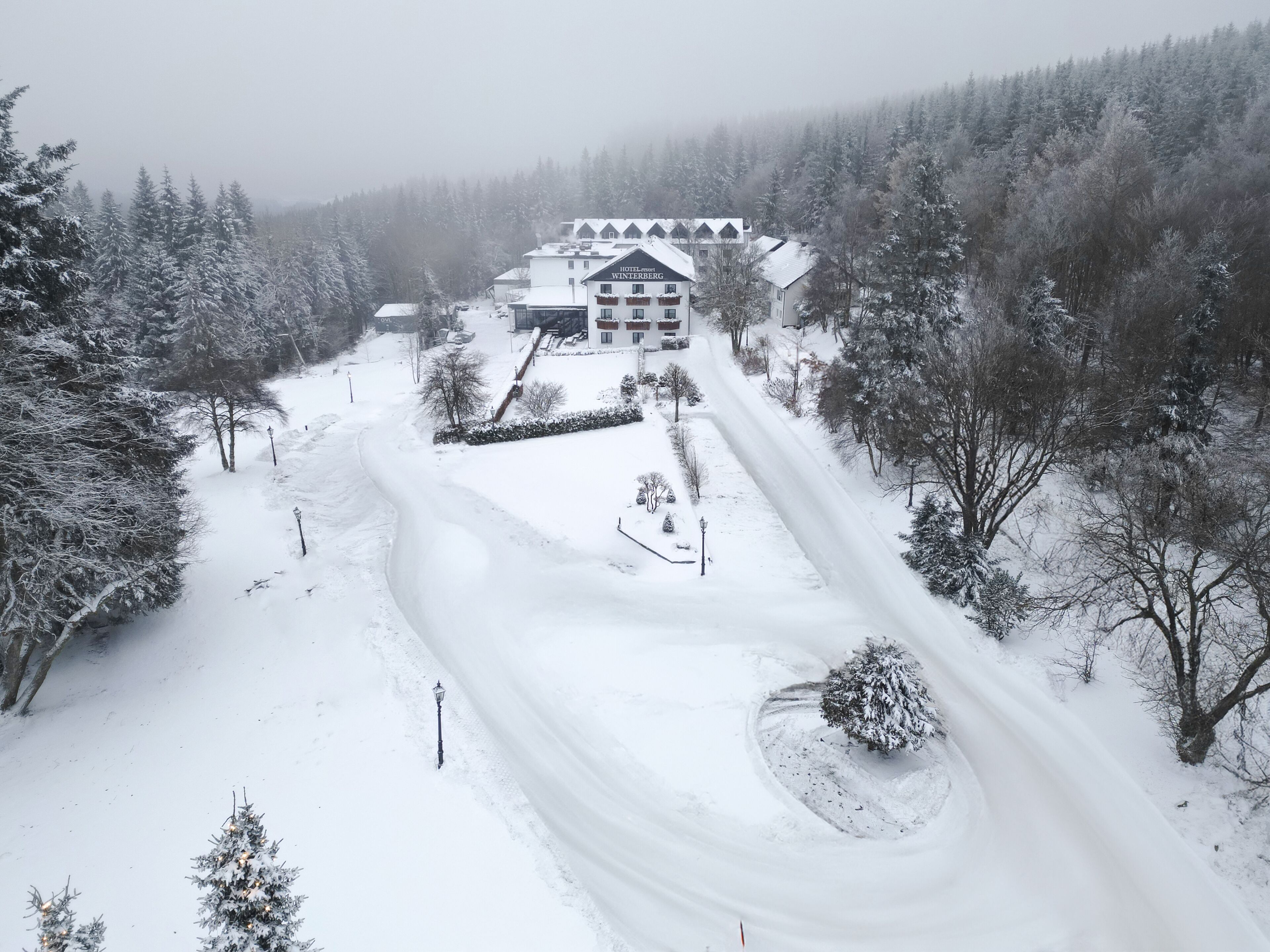 Schneebedeckte Landschaft mit einem im Zentrum befindlichen Gebäude, auf dem 