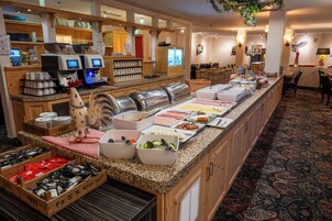 Un'area buffet con diverse postazioni gastronomiche, tra cui una macchina per il caffè e un bancone con contenitori per alimenti.