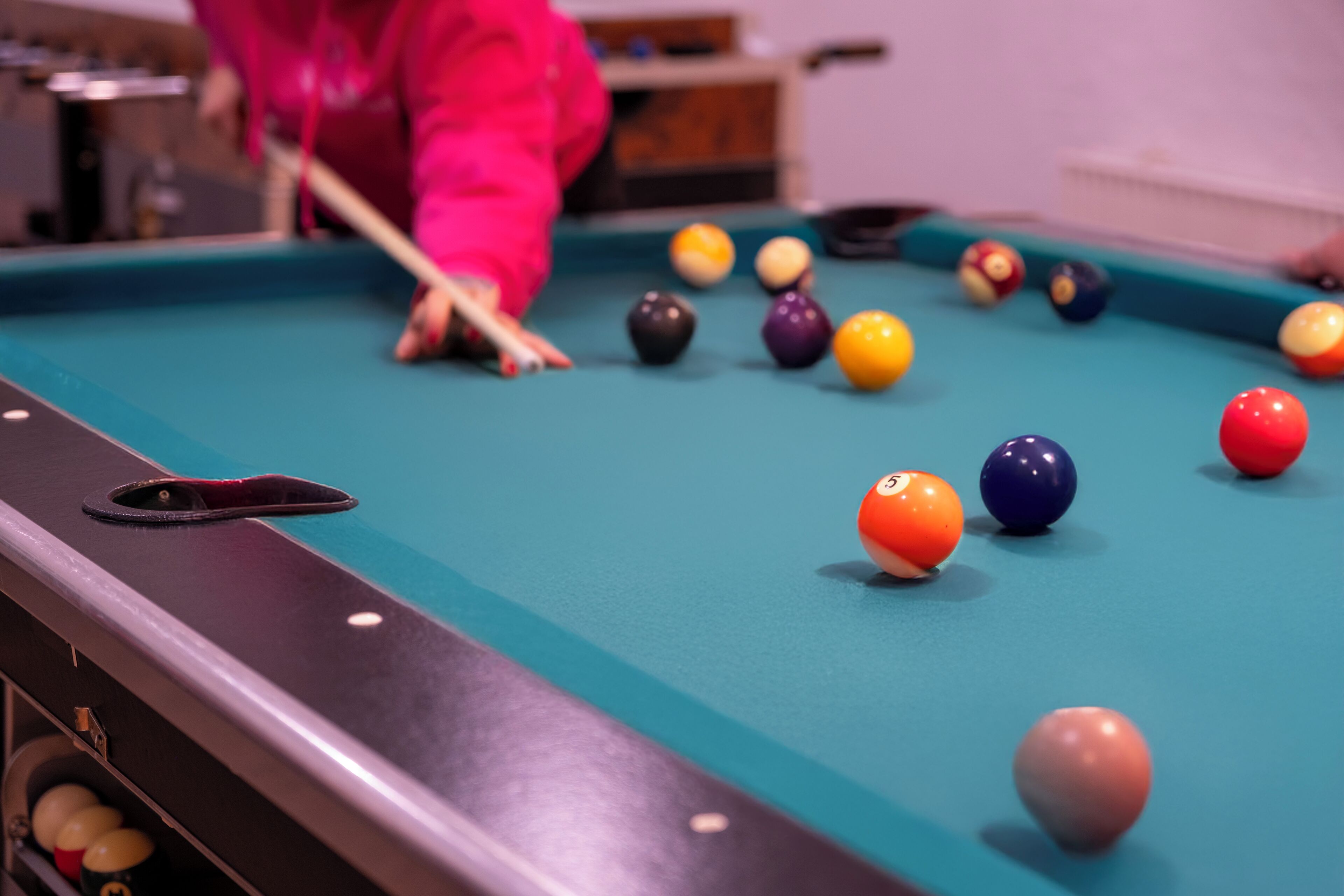 A pool table with balls and a cue stick.