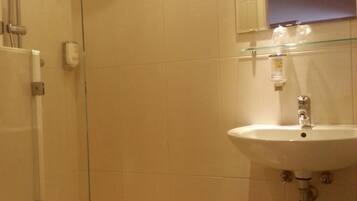 Ein Badezimmer mit Duschkabine aus Glas, Waschbecken und Toilette.