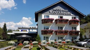 A hotel named "Hotel Winterberg" with a white facade, wooden balconies with flower boxes, and outdoor picnic tables. - Hotel Winterberg Resort (Winterberg)