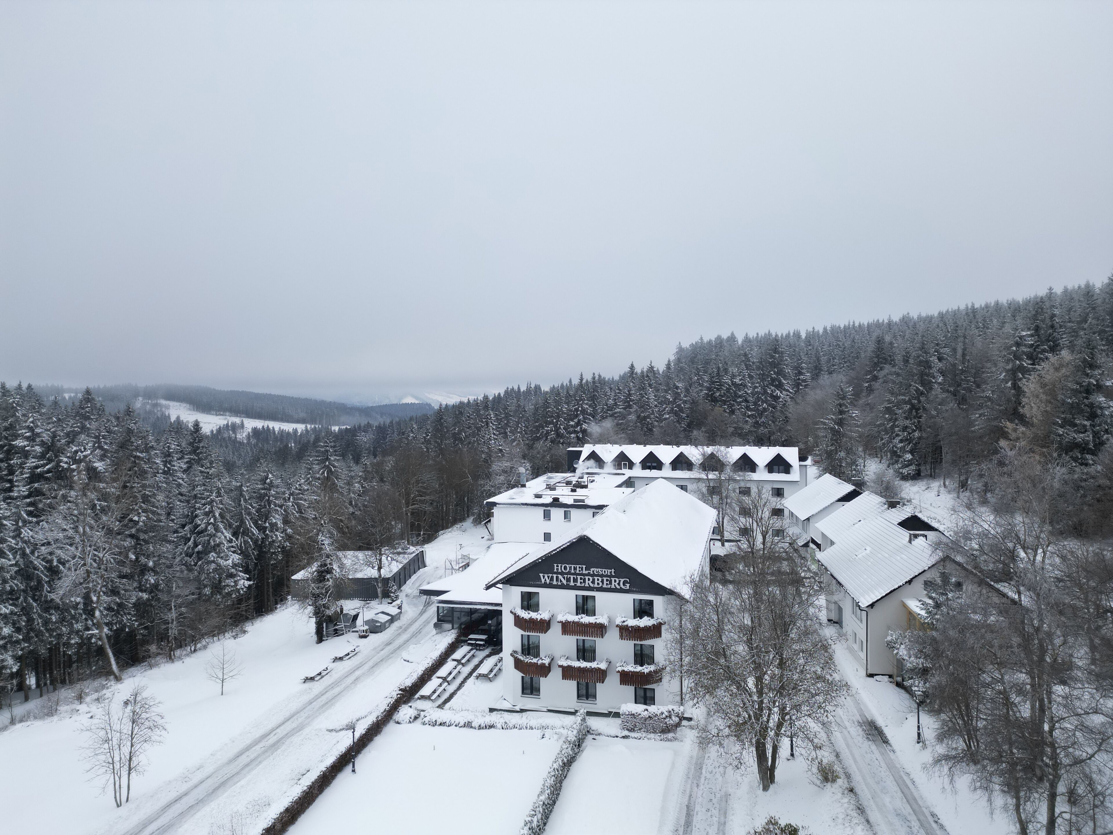A hotel with multiple buildings, a snow-covered landscape, and a forested area in the background.