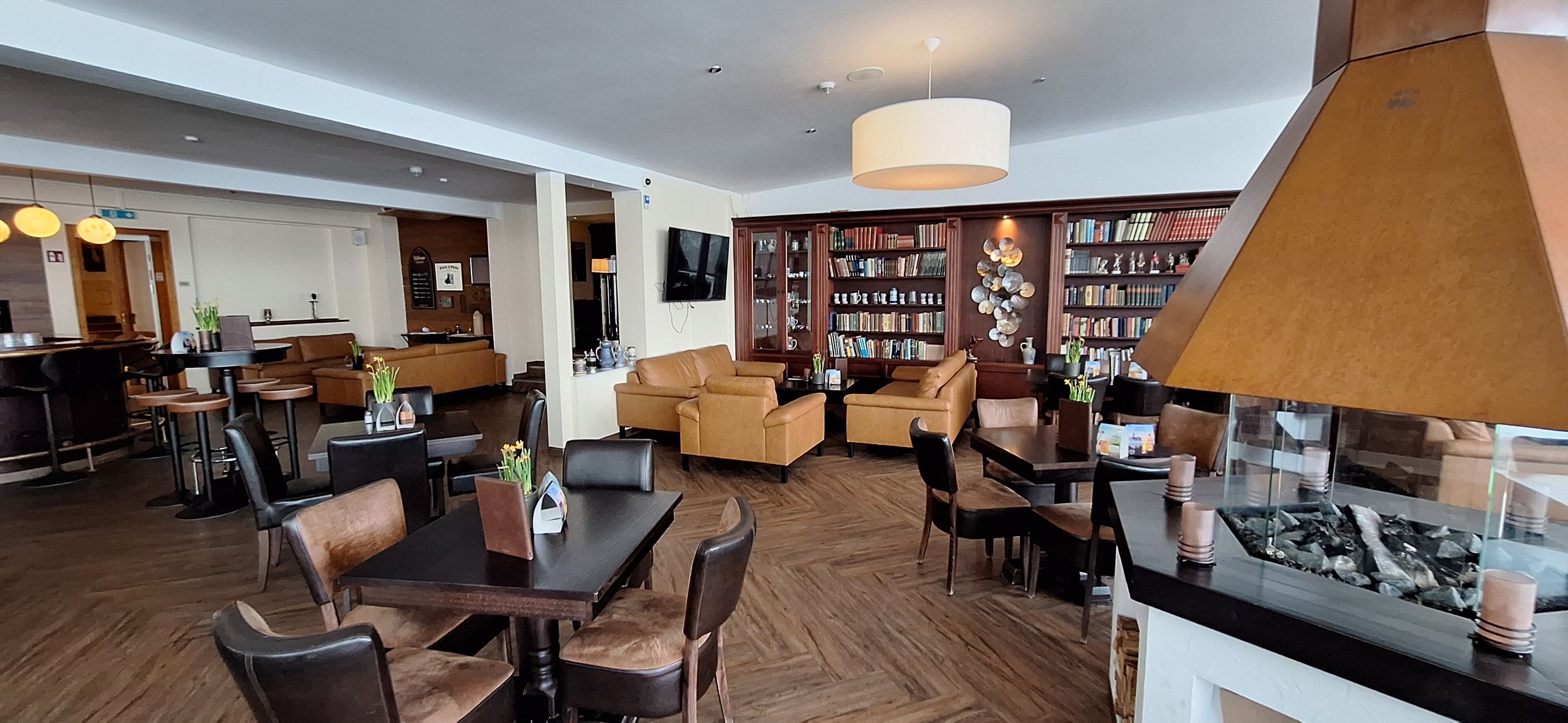 Eine großzügige Hotelhalle mit Essbereich, Sitzgelegenheiten und einem großen Bücherregal voller Bücher.