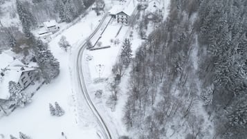 Un paisaje nevado con un hotel llamado "Hotel Winterberg", que cuenta con un edificio central con múltiples ventanas y un techo inclinado.