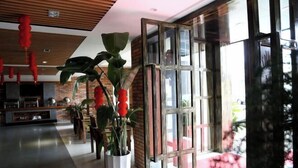 A hotel lobby with a modern design, featuring a brick wall, large windows, and potted plants. - Pai Hotel (Xinchang Wanda Plaza store) (Xinchang)