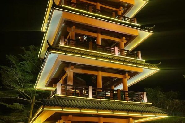 Un edificio de estilo pagoda con varios niveles, barandillas iluminadas y un techo tradicional.