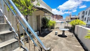Um terraço no telhado com escada de metal, área de estar externa e plantas em vasos.