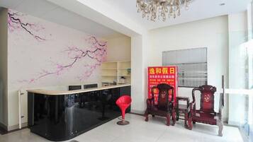 A reception area with a black counter, red chairs, and a chandelier.