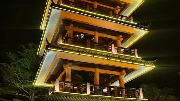 Um edifício em estilo pagode, com vários níveis, detalhes arquitetônicos tradicionais e corrimãos iluminados.