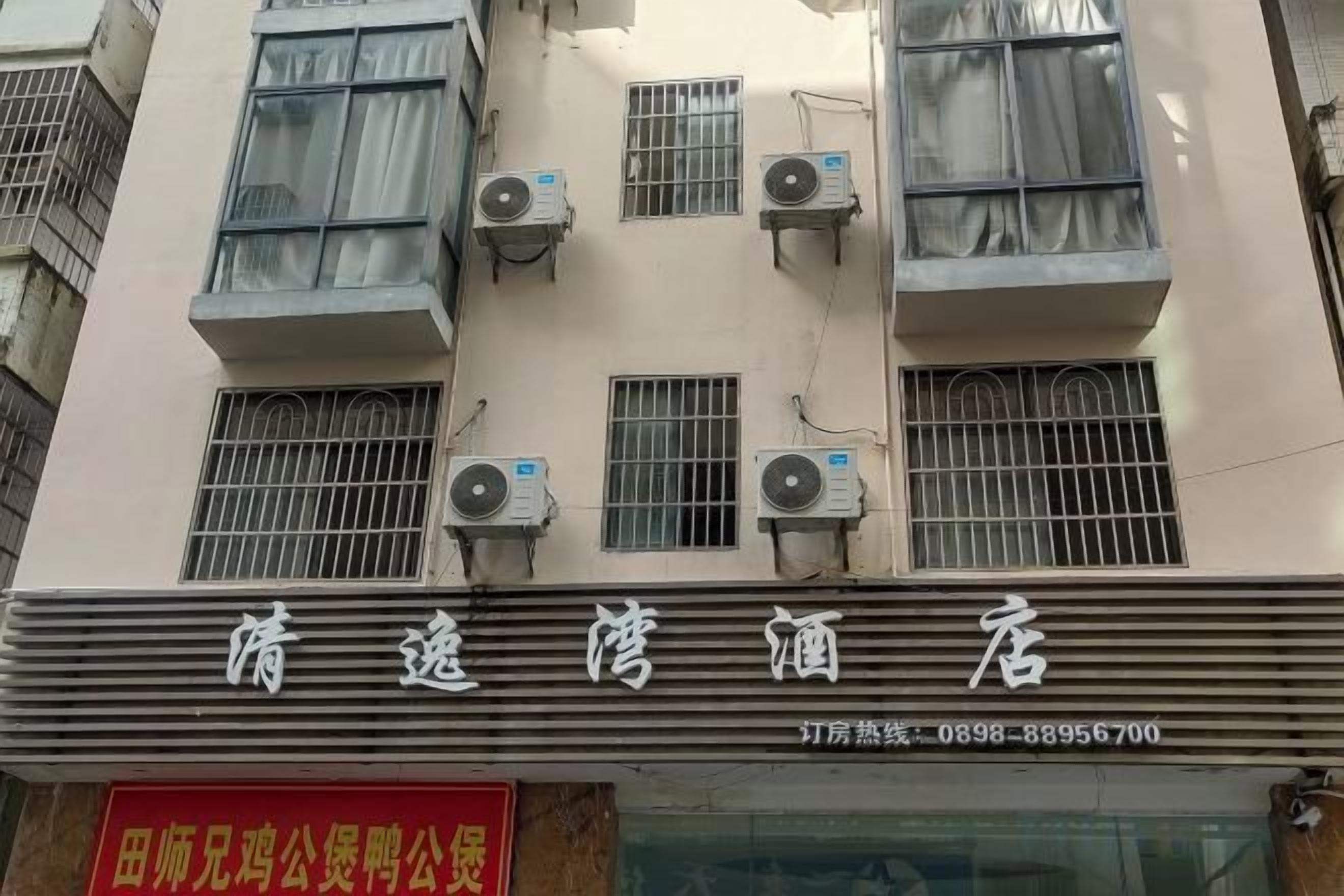 A hotel facade with multiple air conditioning units, a visible signboard, and a red advertisement below.