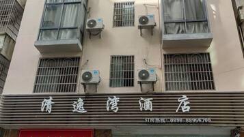 A hotel facade with multiple air conditioning units, a visible signboard, and a red advertisement below.
