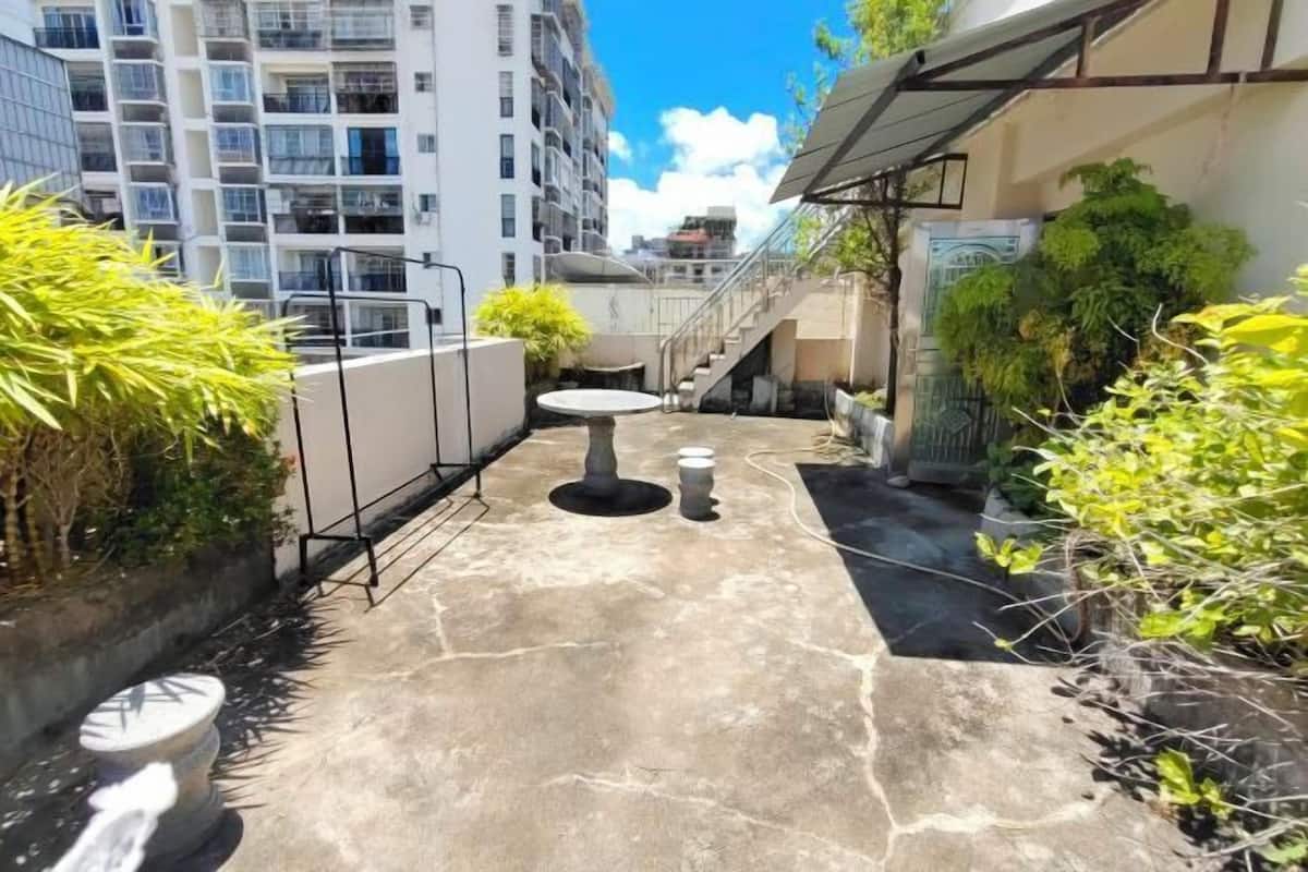A courtyard with a stone floor, a round table, and a staircase leading to an upper level.
