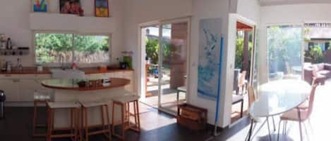 A spacious living area with a large window, a dining table, and a sofa.