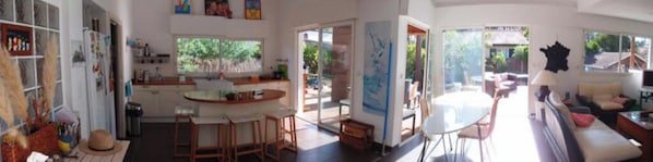 A spacious living area with a large window, a dining table, and a sofa.