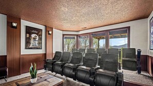 A conference room with a wooden panel wall, a large poster, and a row of black leather chairs with attached cup holders.