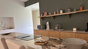 A modern kitchen with a marble countertop, a built-in oven, and wooden cabinets. - Maison Proche lac Hourtin et Océan (Gaillan-en-Médoc)