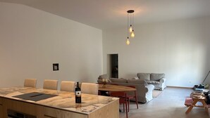 A modern kitchen with a large island, a dining area with a round table, and a living room with a sofa and a coffee table. - Maison Proche lac Hourtin et Océan (Gaillan-en-Médoc)
