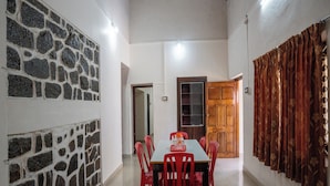A dining area with a stone wall, a wooden door, and red chairs.