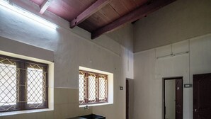 A spacious kitchen with a long countertop and two windows with metal bars.